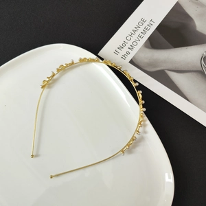Detail of slim gold alloy headband decorated with elegant small white pearls for hair