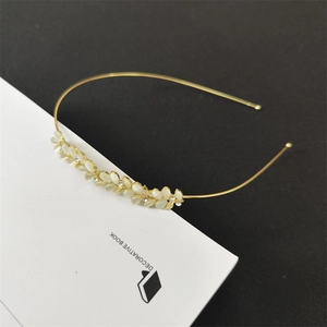 Detail view of a gold metal headband with white cat eye stone petals and crystal centers