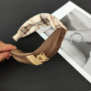 Détail d'un bandeau large en tissu à carreaux marron avec écusson d'ours mignon
