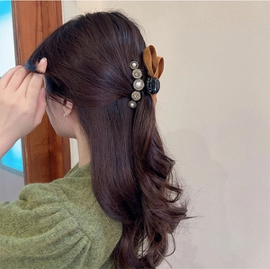 Detailed view of baroque pearl and rhinestone velvet hair claw clip on model hair
