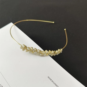 Detail of a thin gold headband with opal petals, small rhinestones and metal leaves
