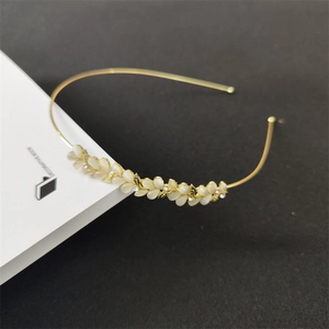 Close-up of golden leaf headband with cat eye stone and rhinestones on book