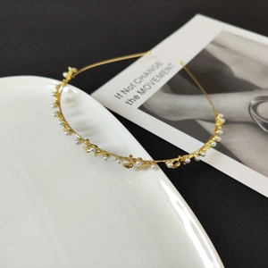 Detailed macro view of a gold floral headband with pearls on white ceramic plate