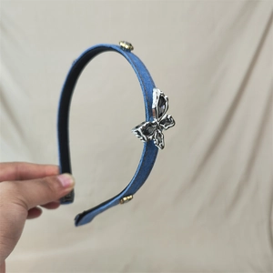 Detail shot of blue denim headband featuring metallic butterfly and crystal stud accents