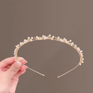 Dettaglio di grappoli di perle su un elegante cerchietto in metallo dorato a mano