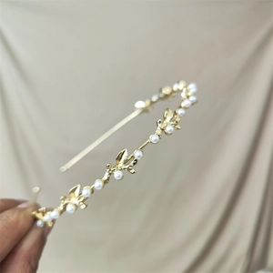 Detail of elegant gold metal headband with white pearls and delicate leaf accents