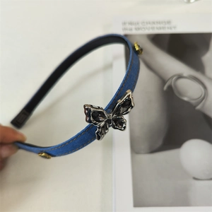 Detail of blue denim headband featuring silver butterfly with crystals and gold accent