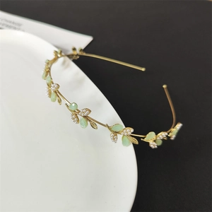 Close-up of golden leaf headband with white pearls on a minimalist ceramic plate