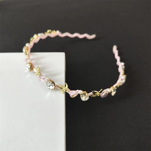 Dettaglio della fascia floreale rosa con strass, farfalle in metallo e perle lucide