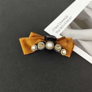 Detail of velvet bow hair claw clip with faux pearls and yellow gemstone inlay