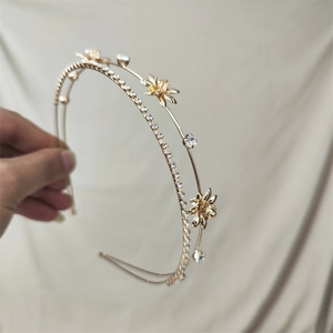 Detailed macro view of a golden double-layered headband with rhinestones and flower charm