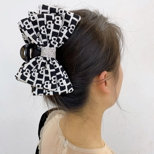 Vista posteriore di una pinza per capelli a fiocco bianco e nero con strass e motivi B
