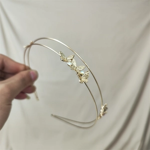 Detail view of a double-layered golden headband featuring delicate rhinestone butterfly accents