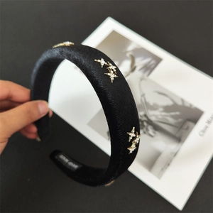 Detail of black satin padded headband featuring golden star studs and white rhinestones