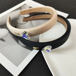 Vue détaillée de serre-têtes rembourrés beige et noir avec strass cœur et plaque dorée
