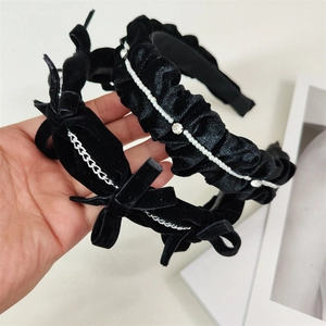 Detail of black velvet headbands with elegant pearl chains and punk style metal accents