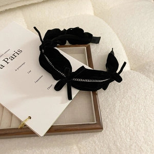 Detail shot of black velvet headband with elegant bow and silver chain link accent