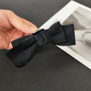 Close-up of elegant black velvet bow hair claw clip with a vintage center button detail