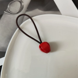 Detail of red tulip hair tie with high elastic brown band on white ceramic tray