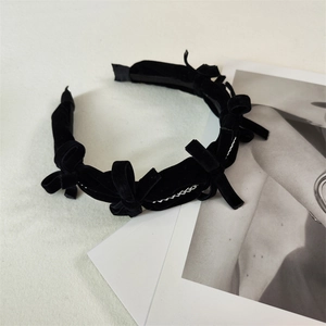 Close-up of black velvet bow headband with silver chain details on minimalist background
