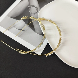 Detail of elegant gold flower headband and pearl hairband set on minimalist background