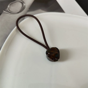 Detail of French tulip hair tie with tortoiseshell texture flower charm on a white ceramic plate