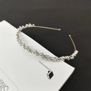 Dettaglio del cerchietto in metallo argento con perle bianche dal design a ramo elegante