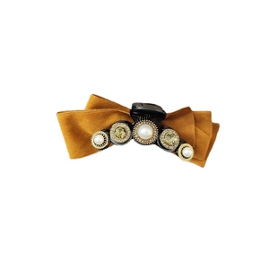 Elegant mustard velvet bow hair claw with baroque pearls and rhinestones on white background