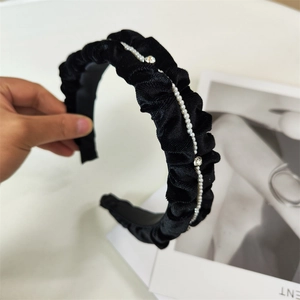 Detailed view of black velvet ruffled headband with white pearls and silver rhinestones