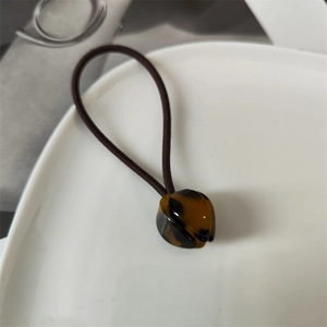 Close-up of handmade tortoiseshell acetate tulip hair tie on a white ceramic plate