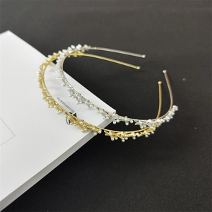 Dettaglio di cerchietti in metallo oro e argento con perle eleganti a forma di ramo