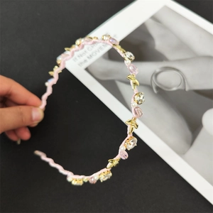 Dettaglio del cerchietto in tessuto rosa con strass di cristallo, perle e fiocchi d'oro