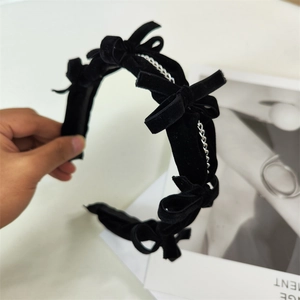 Close-up of black velvet bow headband with silver chain details and retro aesthetic