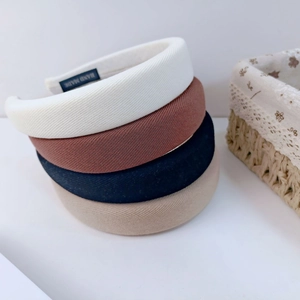 Detailed view of stacked thick sponge headbands in ivory, navy blue, and caramel tones