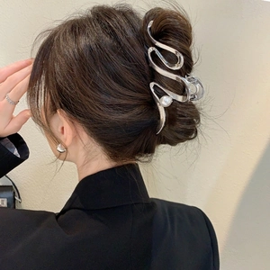 Détail d'une pince à cheveux argentée ondulée avec perle sur une coiffure en chignon