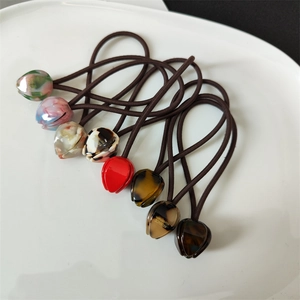 Detail view of eight colorful tulip-shaped acetate hair ties with France Handmade print
