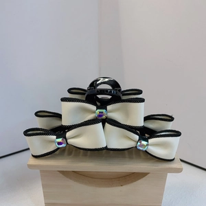 Oversized black hair claw clip with triple cream bows and sparkling rhinestones