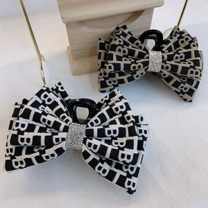 Dettagli di fermagli per capelli a fiocco in tessuto con monogramma TB e strass lucidi