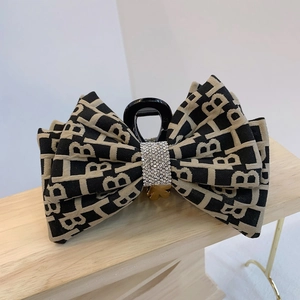 Vista macro della clip per capelli con tessuto a motivo B e dettagli in strass lucidi