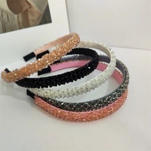 Détail de cinq serre-têtes en perles de cristal multicolores sur un fond blanc épuré