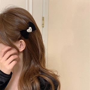 Détail d'une barrette à nœud en velours avec un strass en forme de cœur étincelant