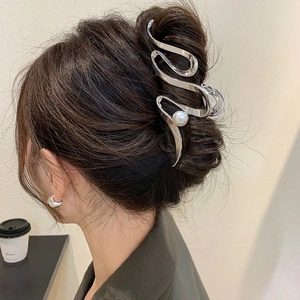 Détail d'une pince à cheveux argentée avec perle pour un style de coiffure minimaliste