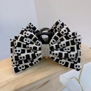 Dettaglio del fermaglio per capelli con fiocco bianco e nero e centro con strass lucidi