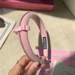 Detailed close-up of a pink velvet headband with rhinestones and a silk satin bow