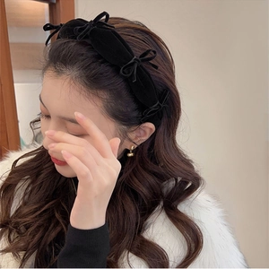 Close-up of a black velvet headband with multiple bow accents on a female model