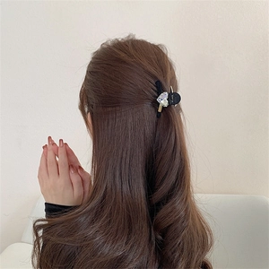 Vue arrière d'une mini pince à cheveux noire avec strass en forme de cœur clair