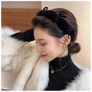 Detail view of a vintage black velvet bow headband with delicate chain accents for women