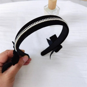 Detail of vintage black velvet headband featuring faux pearls, rhinestones and a side bow