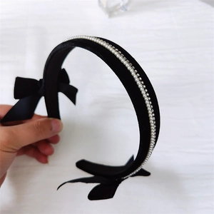 Close-up of black velvet headband featuring white pearls, rhinestones and double side bows