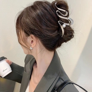 Pince à cheveux ondulée argentée avec perle présentée sur un chignon français élégant